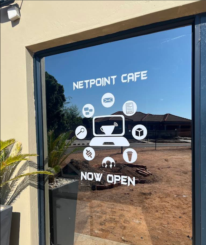 NETPOINT CAFE storefront glass with now open sign